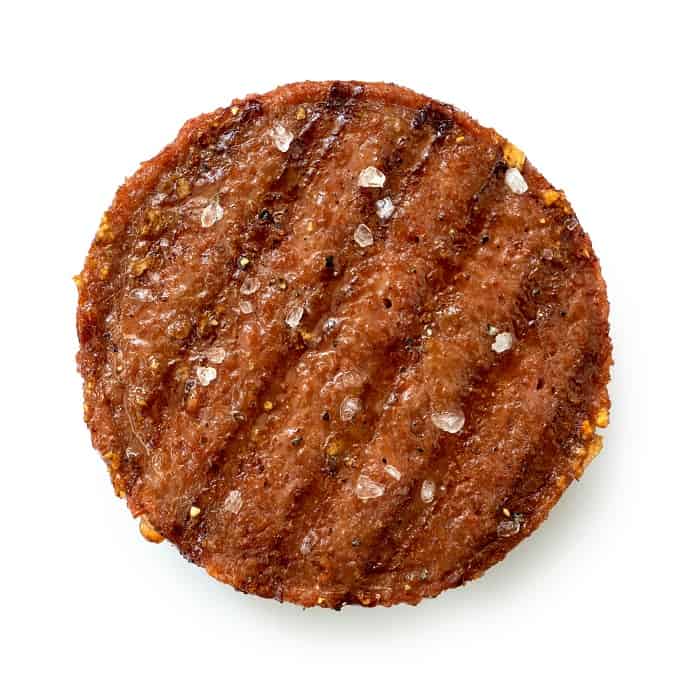 Plant based grilled burger patty with grill marks and rock salt isolated on white. Top view.