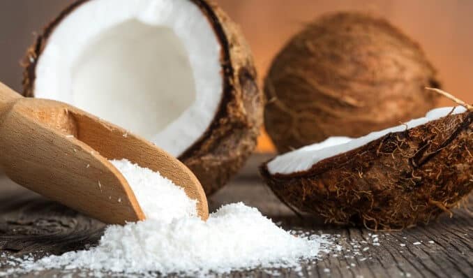 Close up of a coconut and grounded coconut flakes