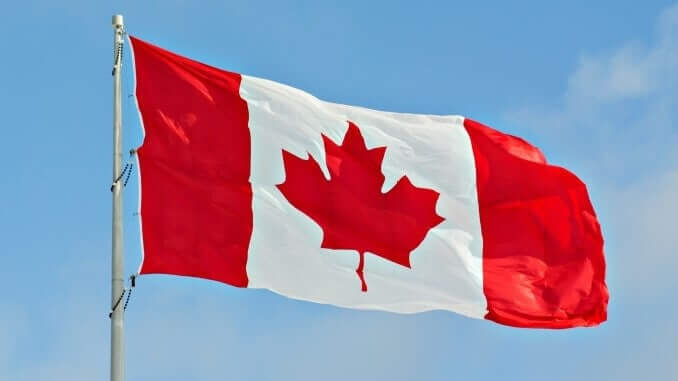 Flag of Canada flying against a blue sky.