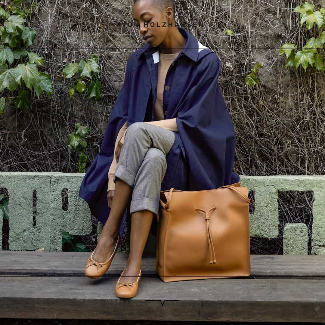 a woman with a vegan bamboo leather brown bag and shoes sitting outdoors