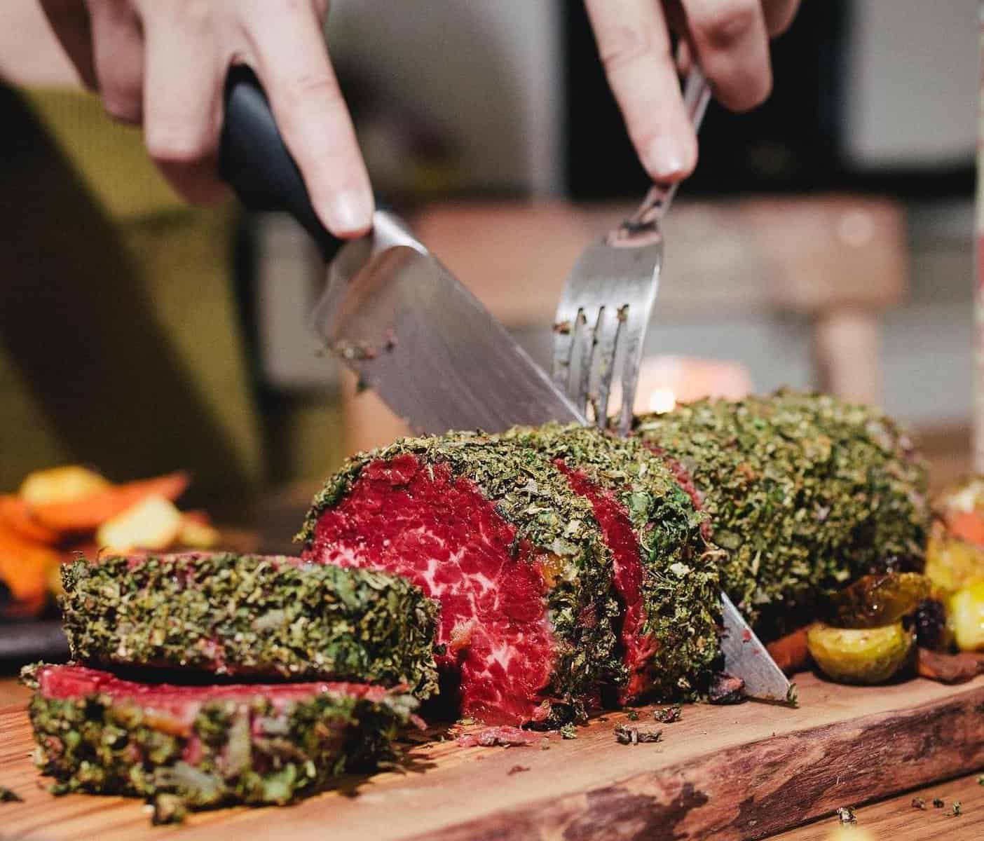 juicy marbles' plant-based whole cut loin pictured on a wooden board and being cut by a man