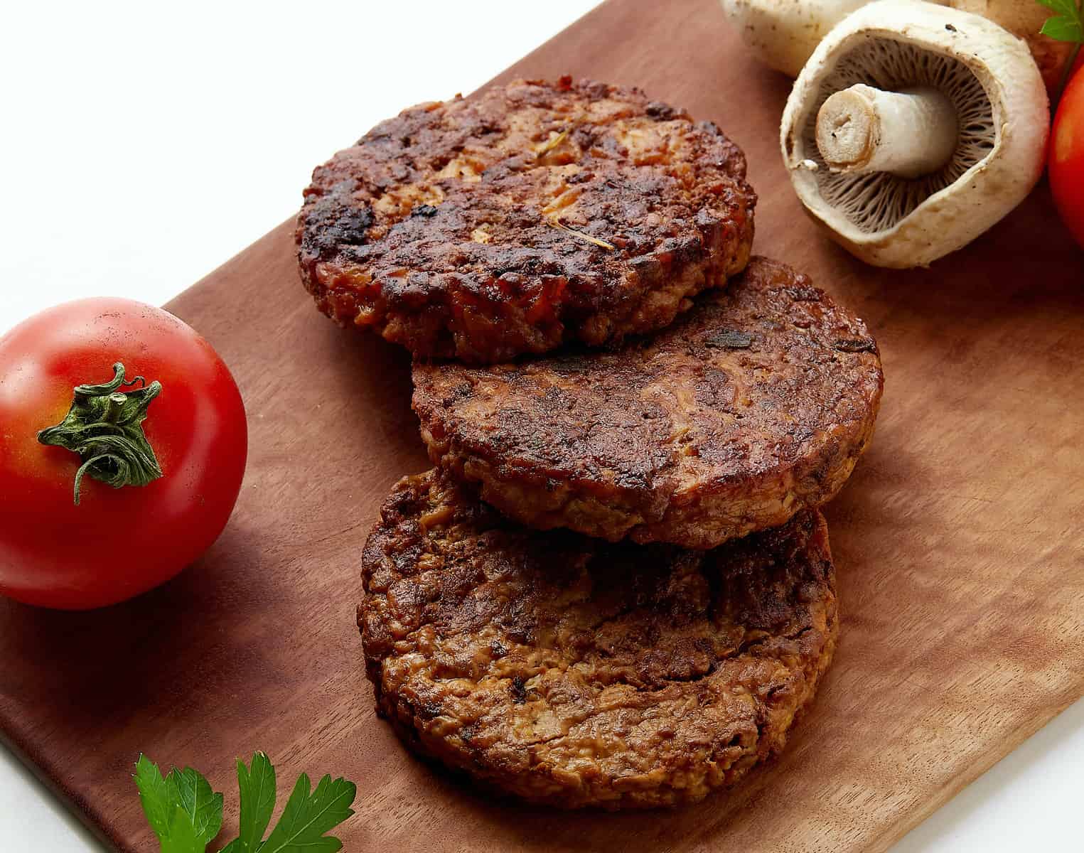 three mycelium based burgers on top of a wooden board