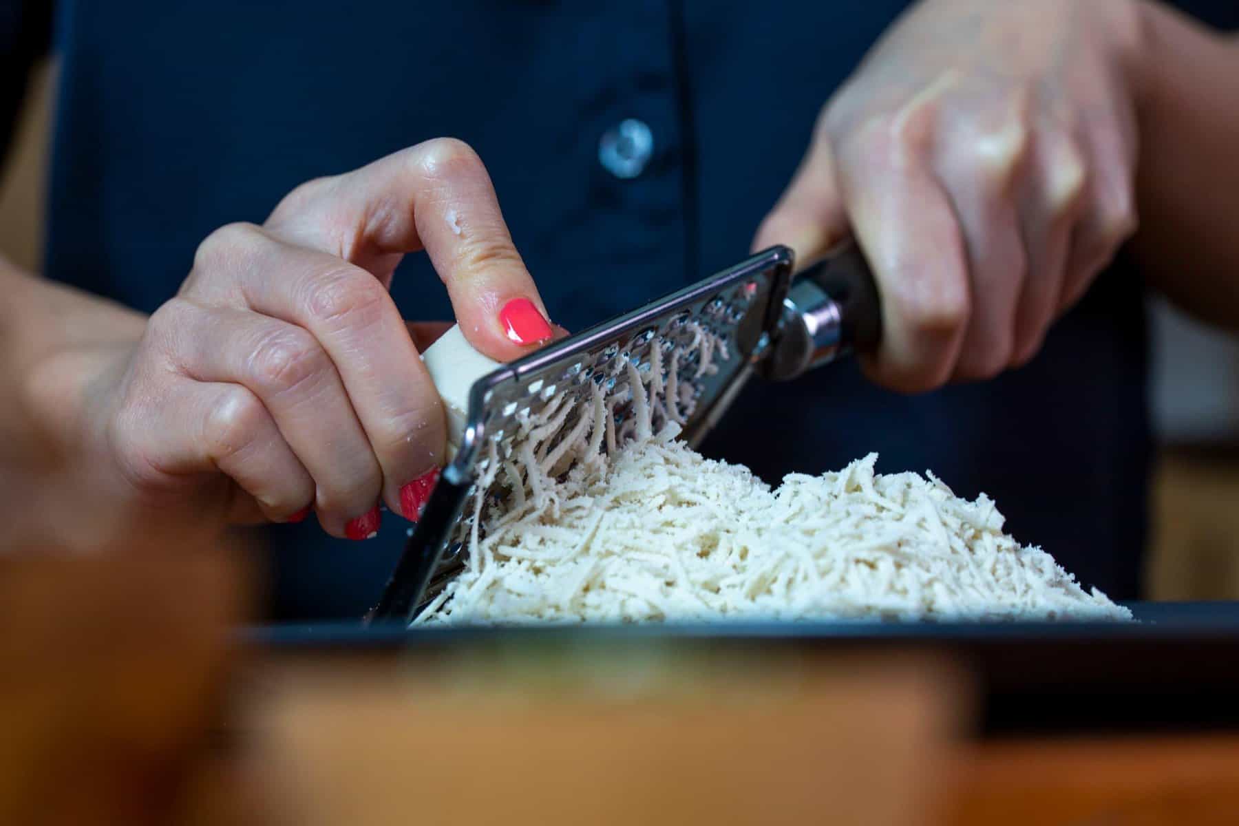 animal free mozzarella cheese being grated by a woman