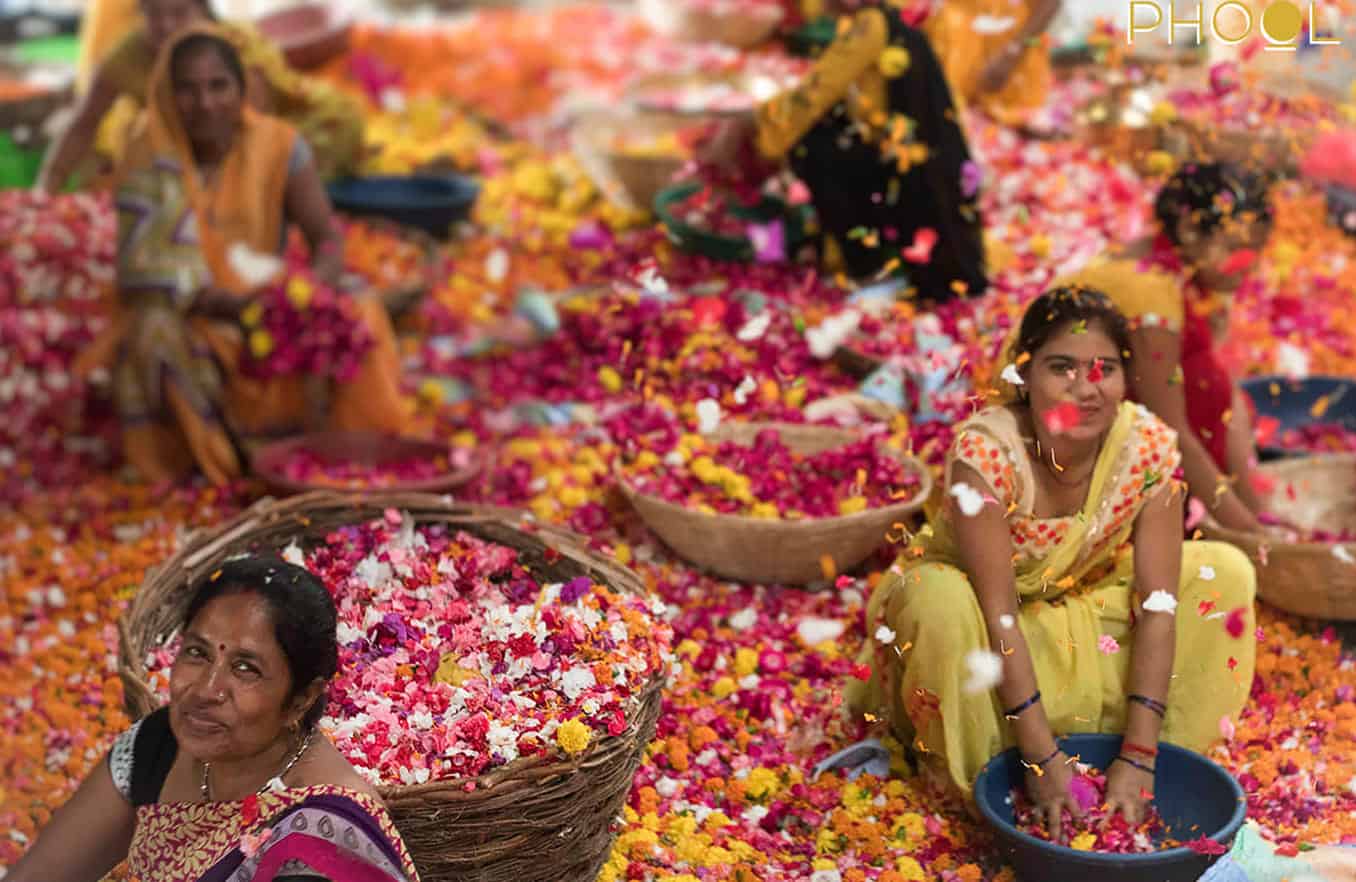 phool's women employees sitting on the grown working with colourful flowers